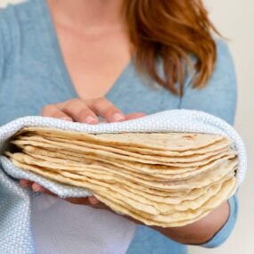 Kelly Senyei holding a stack of homemade tortillas in a blue napkin