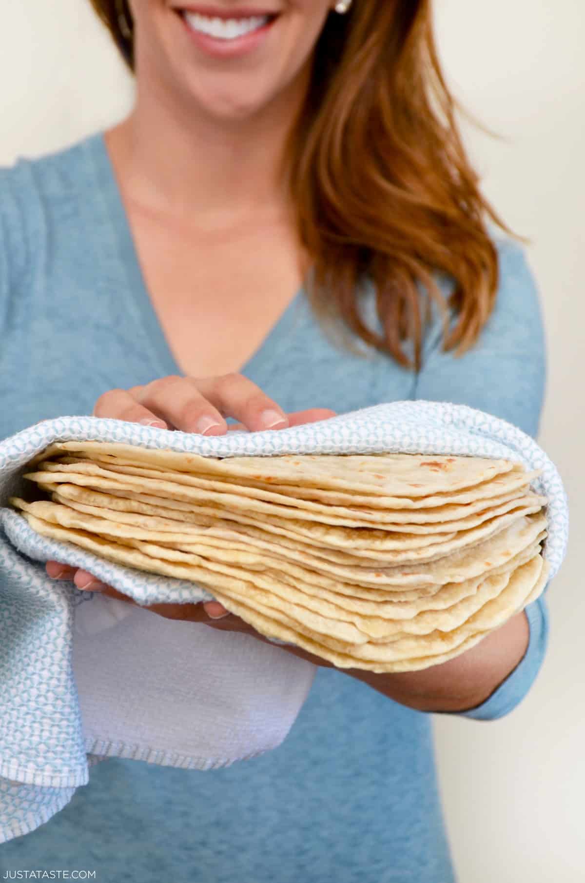 Kelly Senyei holding a stack of homemade tortillas in a blue towel.