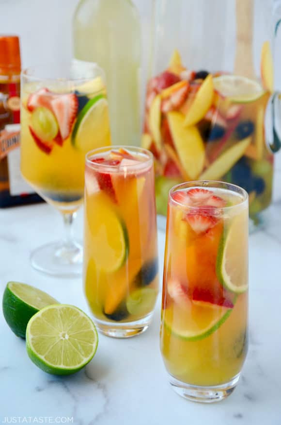 Various glasses filled with the best homemade white sangria with strawberries, limes, apples, grapes, blackberries and peaches