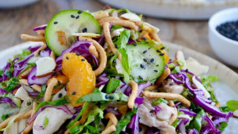 Chinese chicken salad with cucumbers, mandarin oranges, crispy chow mein noodles, shredded purple cabbage and romaine lettuce all tossed in a sesame dressing and garnished with black sesame seeds.