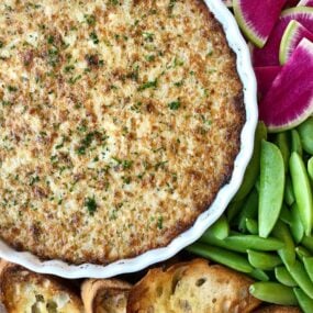 A white dish of Crack Dip surrounded by veggies and bread