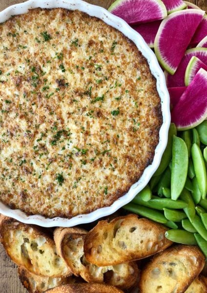 A white dish of Crack Dip surrounded by veggies and bread