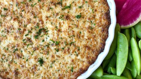 A white dish of Crack Dip surrounded by veggies and bread