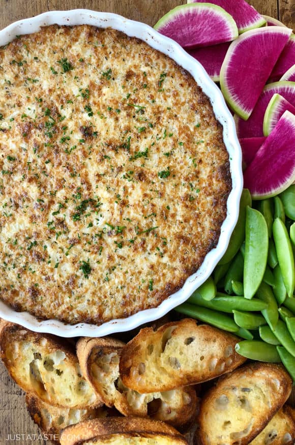 A white dish of Crack Dip surrounded by veggies and bread