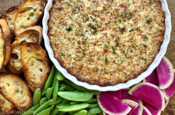 A white dish of Crack Dip surrounded by watermelon radishes, snap peas and toasts