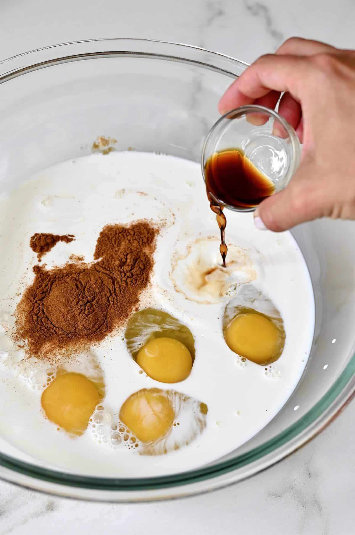 Whisking together cinnamon, allspice, eggs, half-and-half, and vanilla extract to make a custard.