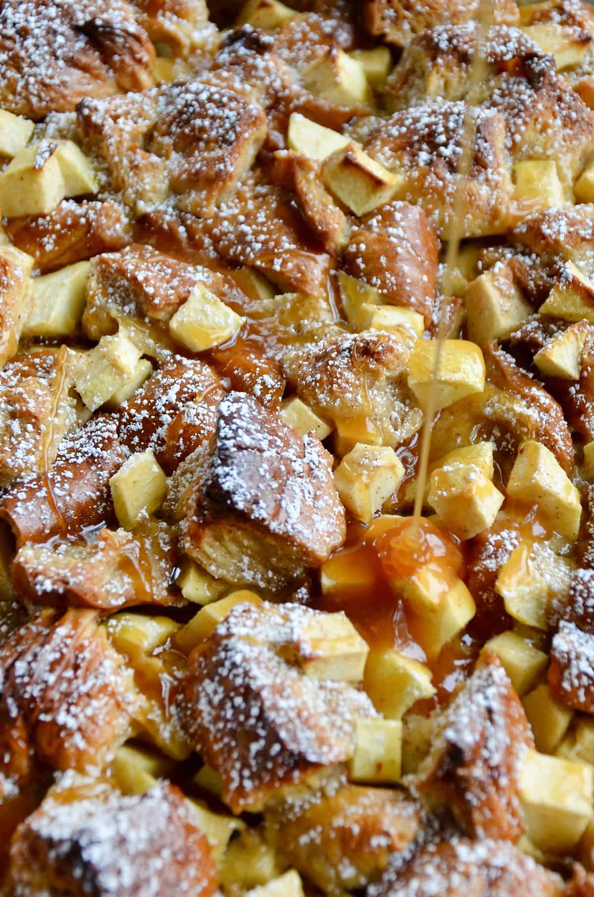 Caramel sauce is being drizzled atop freshly baked apple pudding.