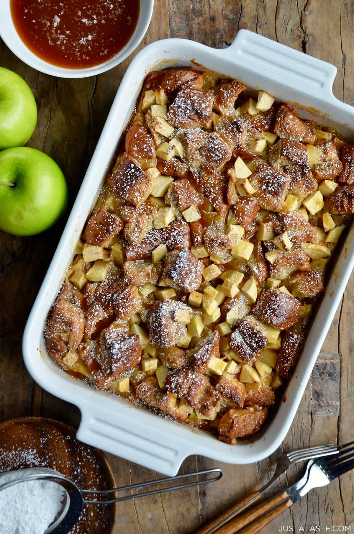 Apple bread pudding with chopped green apples visible, in a white 9x13 baking dish.
