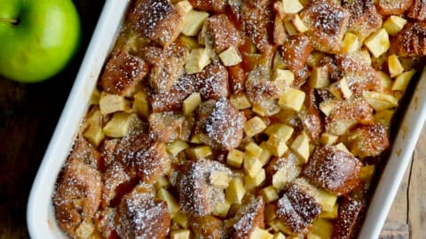 Apple bread pudding with chopped green apples visible, in a white 9x13 baking dish.