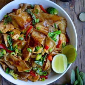 Drunken noodles with wide rice noodles, chicken, veggies and Thai basil in a bowl.