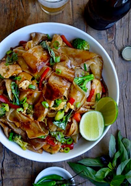Drunken noodles with wide rice noodles, chicken, veggies and Thai basil in a bowl.
