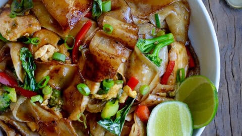 Drunken noodles with wide rice noodles, chicken, veggies and Thai basil in a bowl.