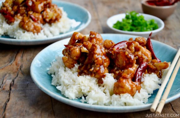 Blue plate containing Homemade General Tso's Cauliflower, white rice and chopsticks