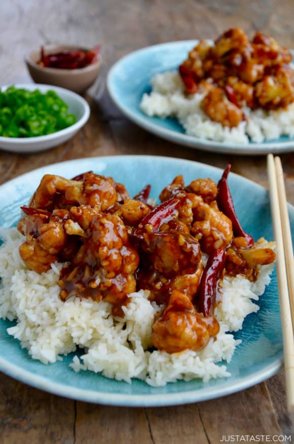 Easy General Tso's Cauliflower over white rice on blue plate with chopsticks