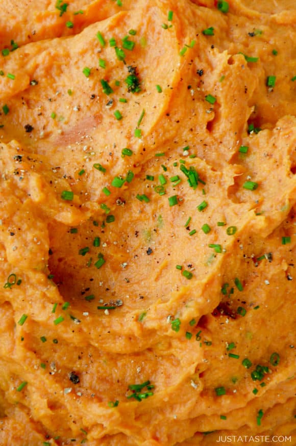 Closeup view of mashed sweet potatoes garnished with chives, salt and pepper
