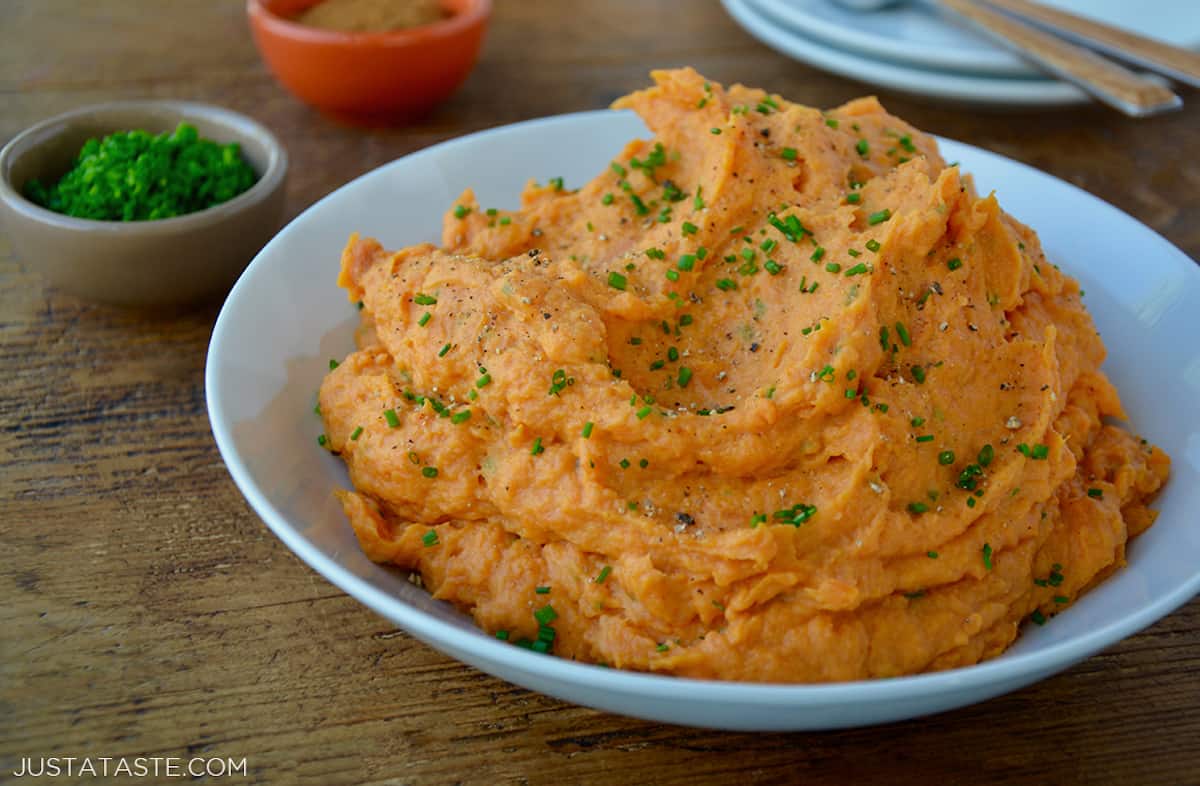 Creamy sweet mashed potatoes garnished with fresh chives in a large serving bowl.