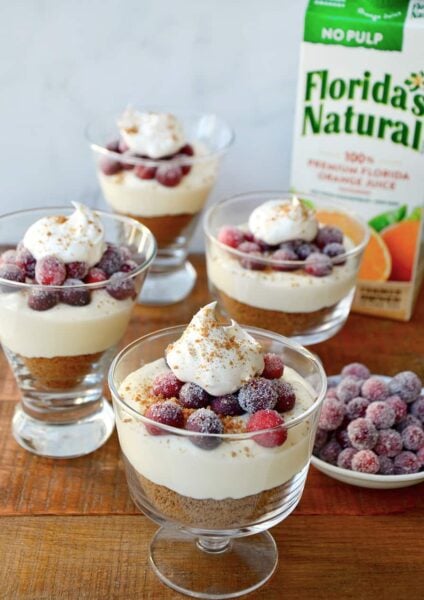 Glass parfait glasses filled with cheese and a carton of orange juice in the background