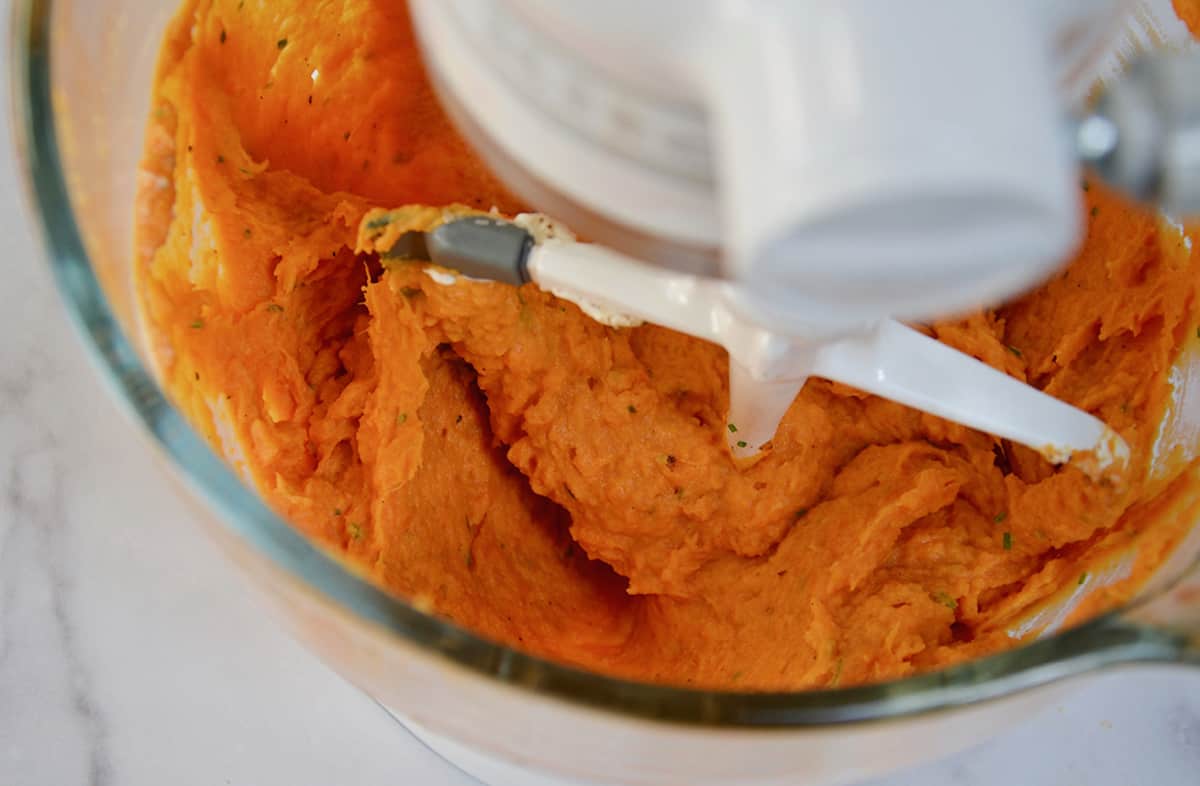 Whipped sweet potatoes in a stand mixer bowl with the paddle attachment.