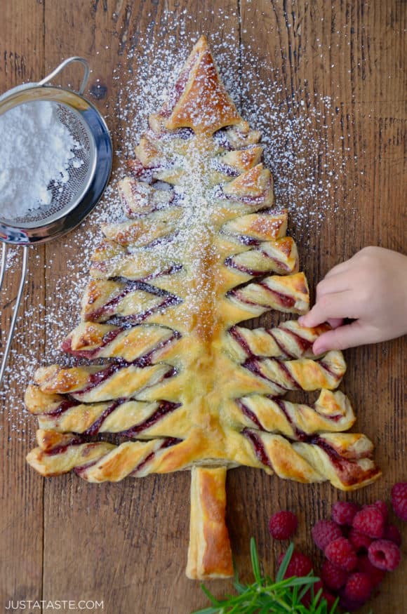 Child's hand reaching for a Christmas Tree Puff Pastry sprinkled with confectioners' sugar