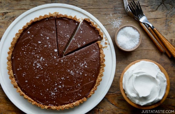 Chocolate-Peanut Butter Pretzel Tart next to bowls containing whipped cream and sea salt