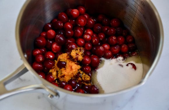 Saucepan containing fresh cranberries, sugar, Grand Marnier and orange zest