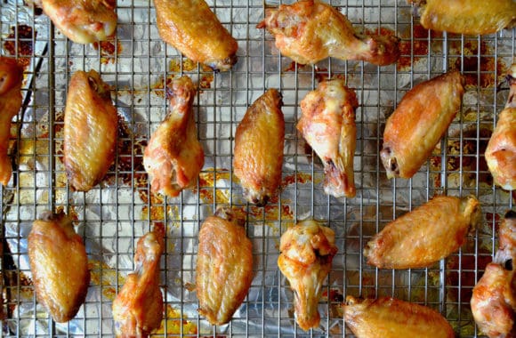 A baking rack atop foil with browned chicken wings on top