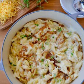 A pot of mac and cheese with caramelized onions and small bowls surrounding it