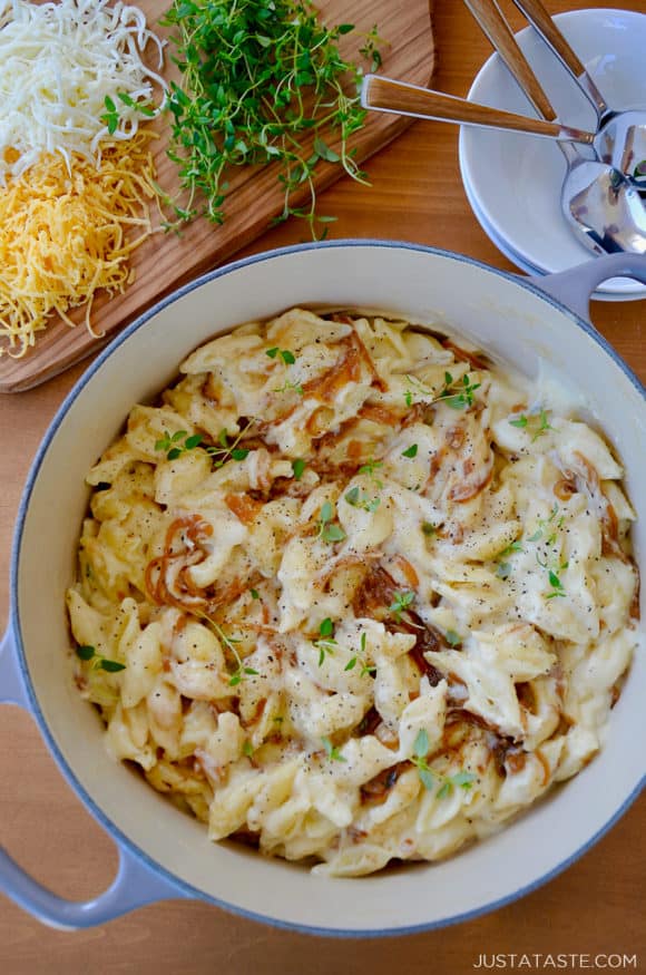 A pot of mac and cheese with caramelized onions and small bowls surrounding it