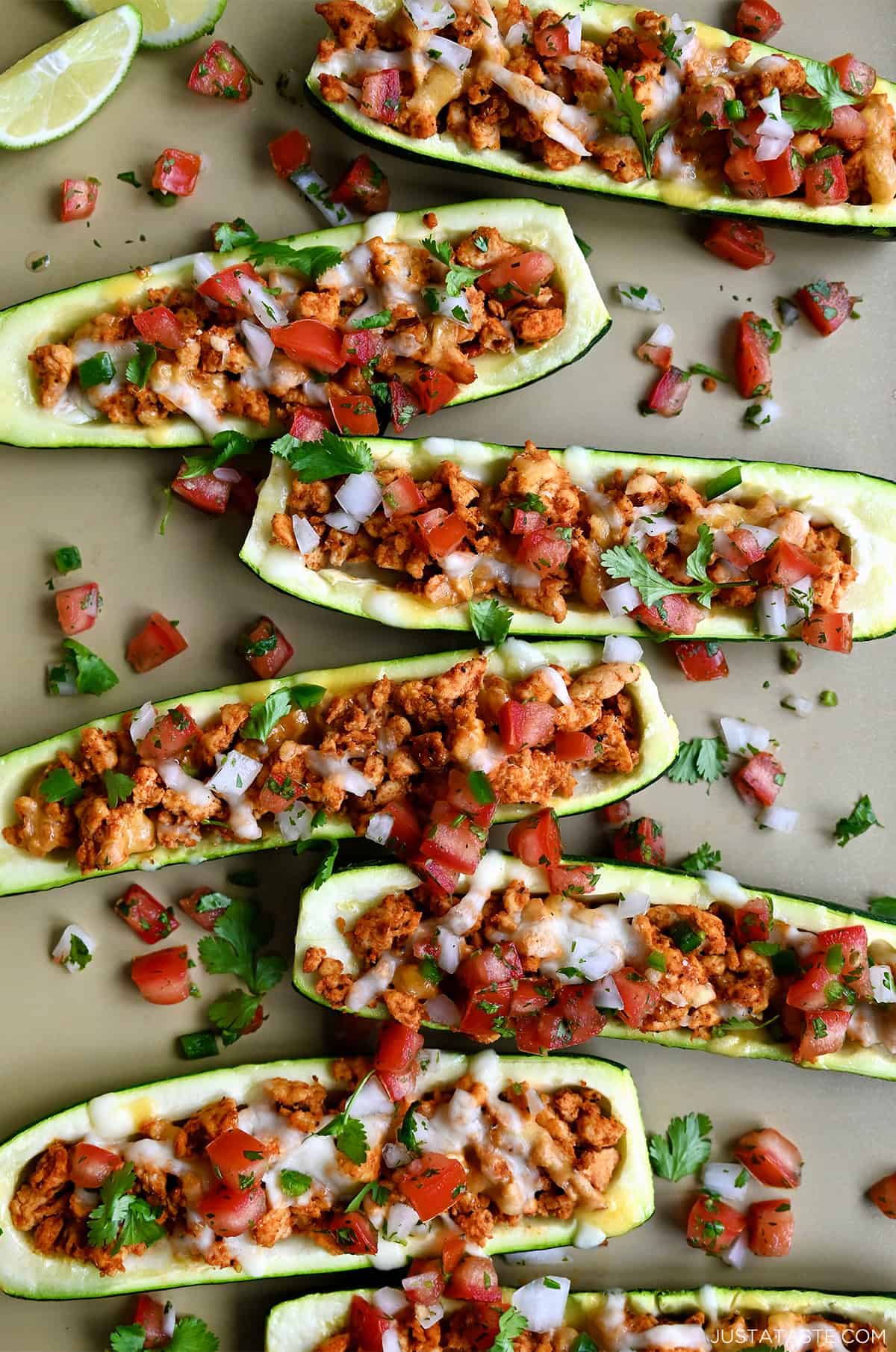 Healthy Zucchini Boats filled with taco-seasoned ground turkey, cheese, and topped with fresh cilantro and pico de gallo on a baking sheet.