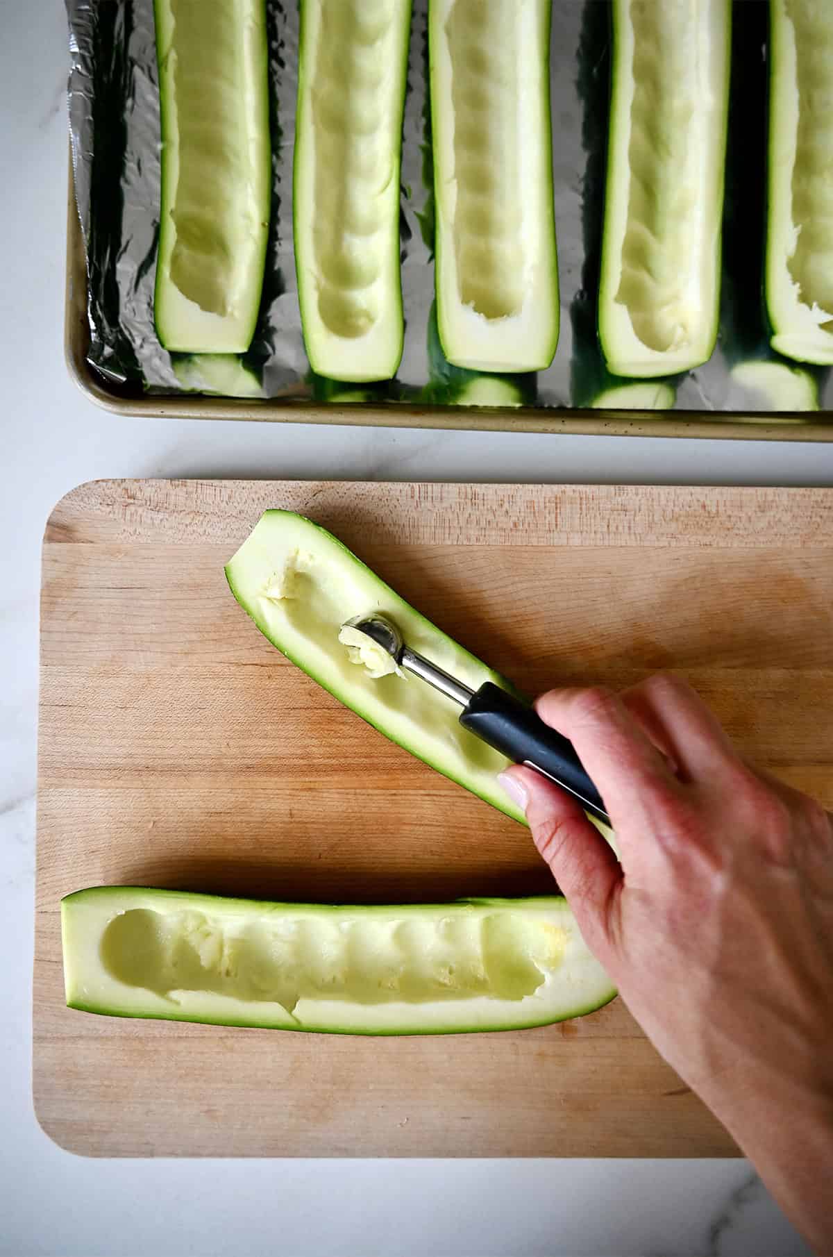 Scooping out the centers of zucchini with a melon baller.