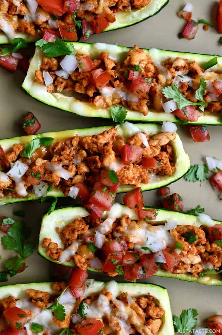 Healthy Stuffed Zucchini Boats filled with seasoned ground turkey, topped with melted cheese, cilantro and pico de gallo.