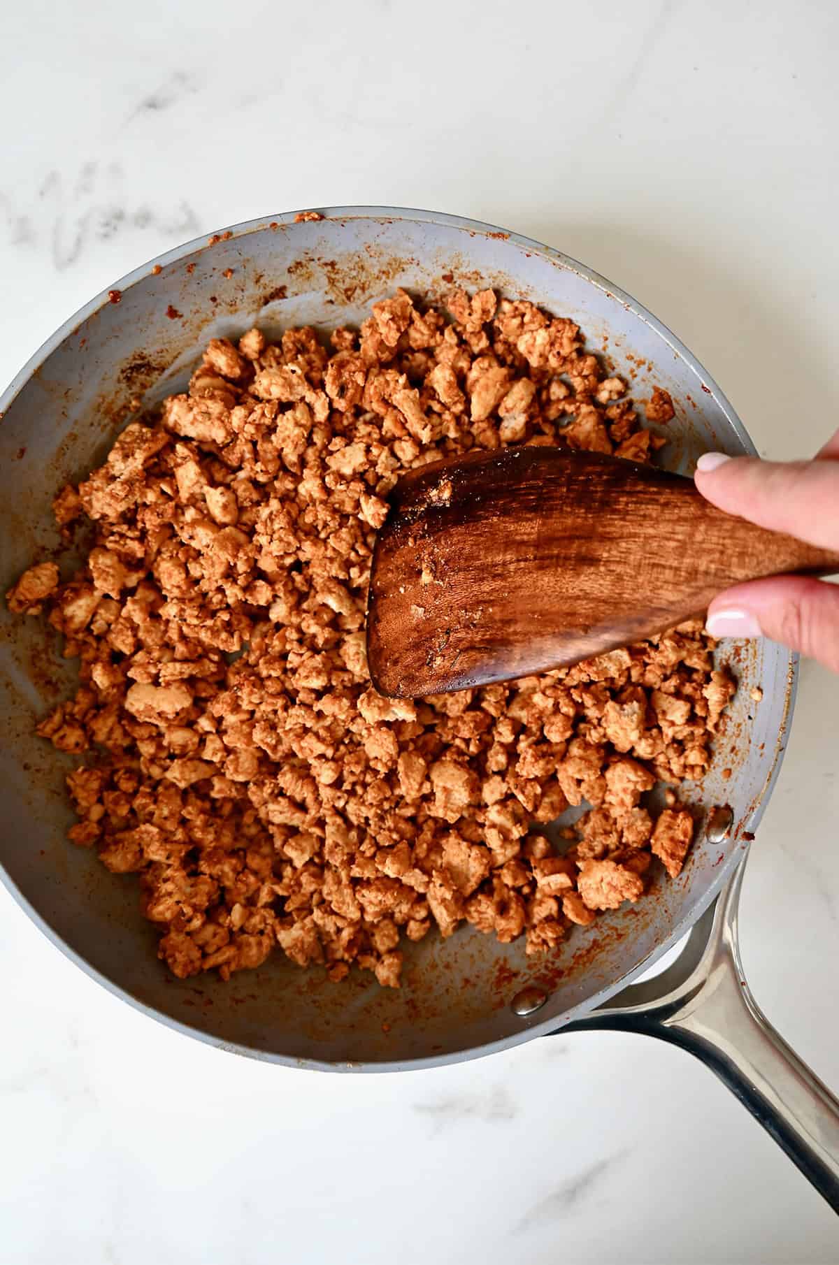 Browned turkey taco meat in a skillet with a wooden spatula.