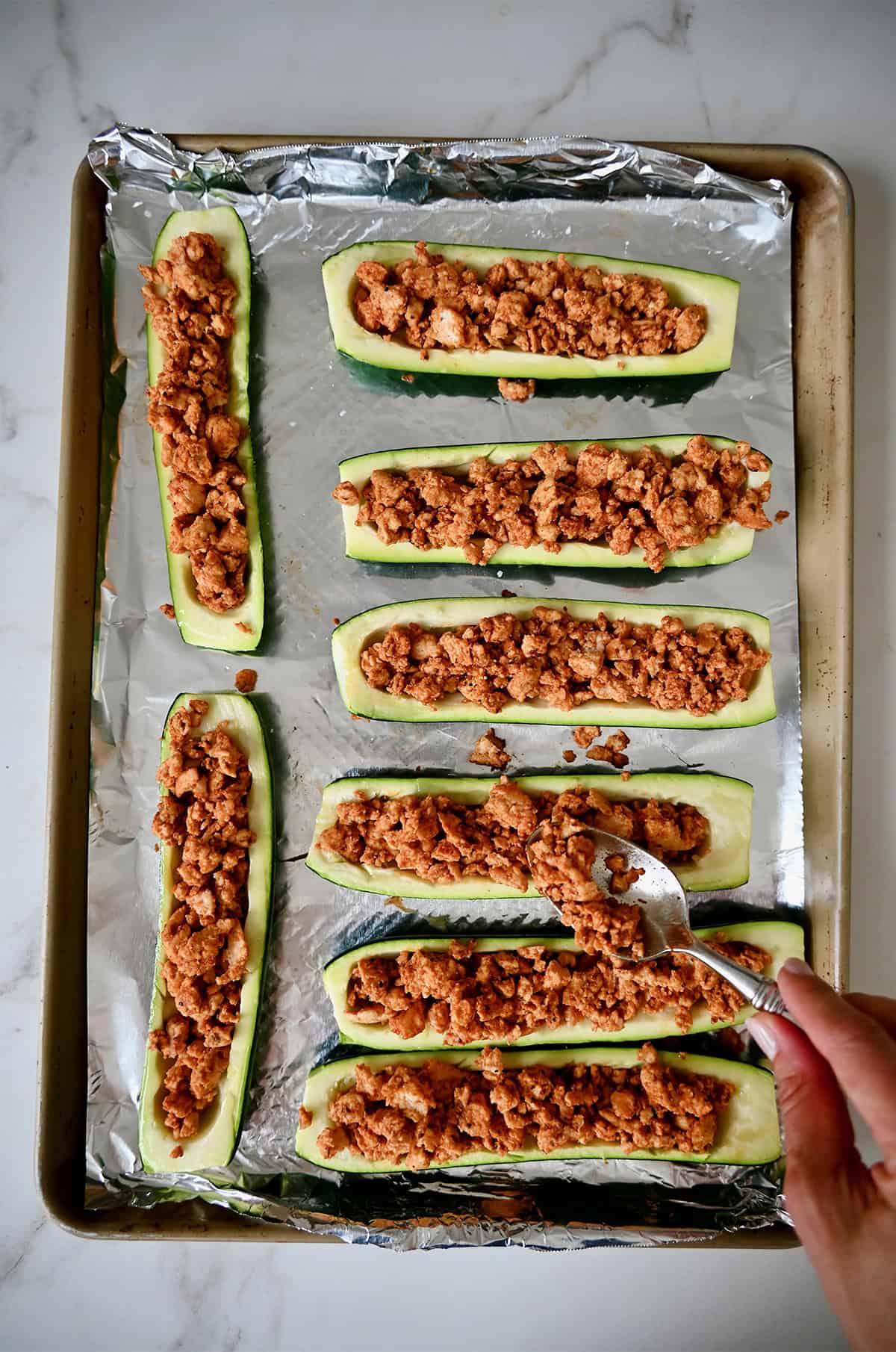 Stuffing zucchini boats with a taco-seasoned ground meat filling.