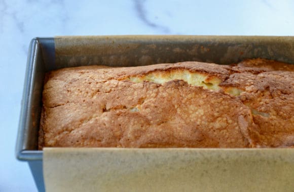 Parchment paper lined loaf pan containing freshly baked cake