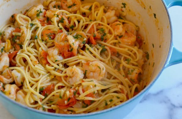 Large pot containing linguine pasta, shrimp, cherry tomatoes, parsley and garlic