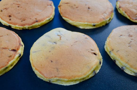 Ricotta chocolate chip pancakes cooking on a griddle