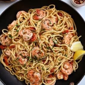 A large skillet containing Quick Shrimp Scampi with cherry tomatoes, chili flakes and fresh herbs