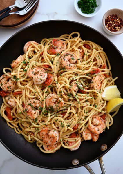 A large skillet containing Quick Shrimp Scampi with cherry tomatoes, chili flakes and fresh herbs
