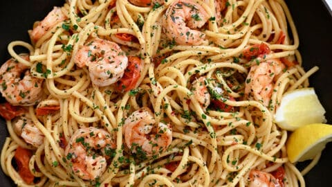 A large skillet containing Quick Shrimp Scampi with cherry tomatoes, chili flakes and fresh herbs