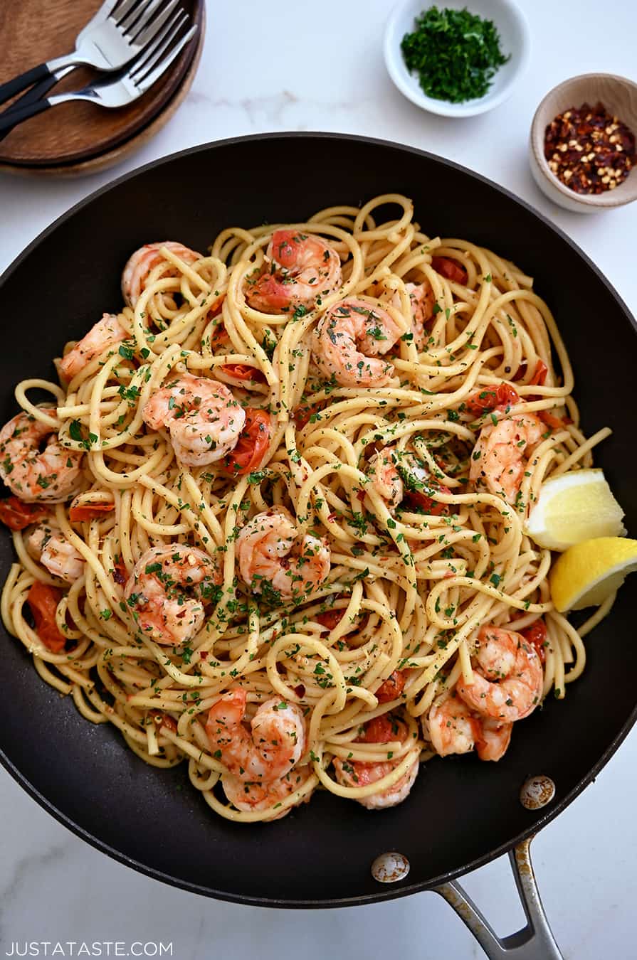 A large skillet containing Quick Shrimp Scampi with cherry tomatoes, chili flakes and fresh herbs