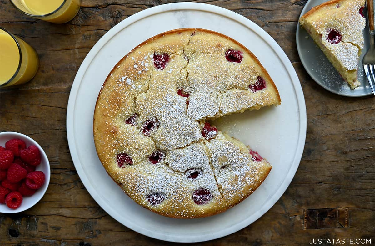 Raspberry cream cheese coffee cake dusted with powdered sugar on a round serving plate.