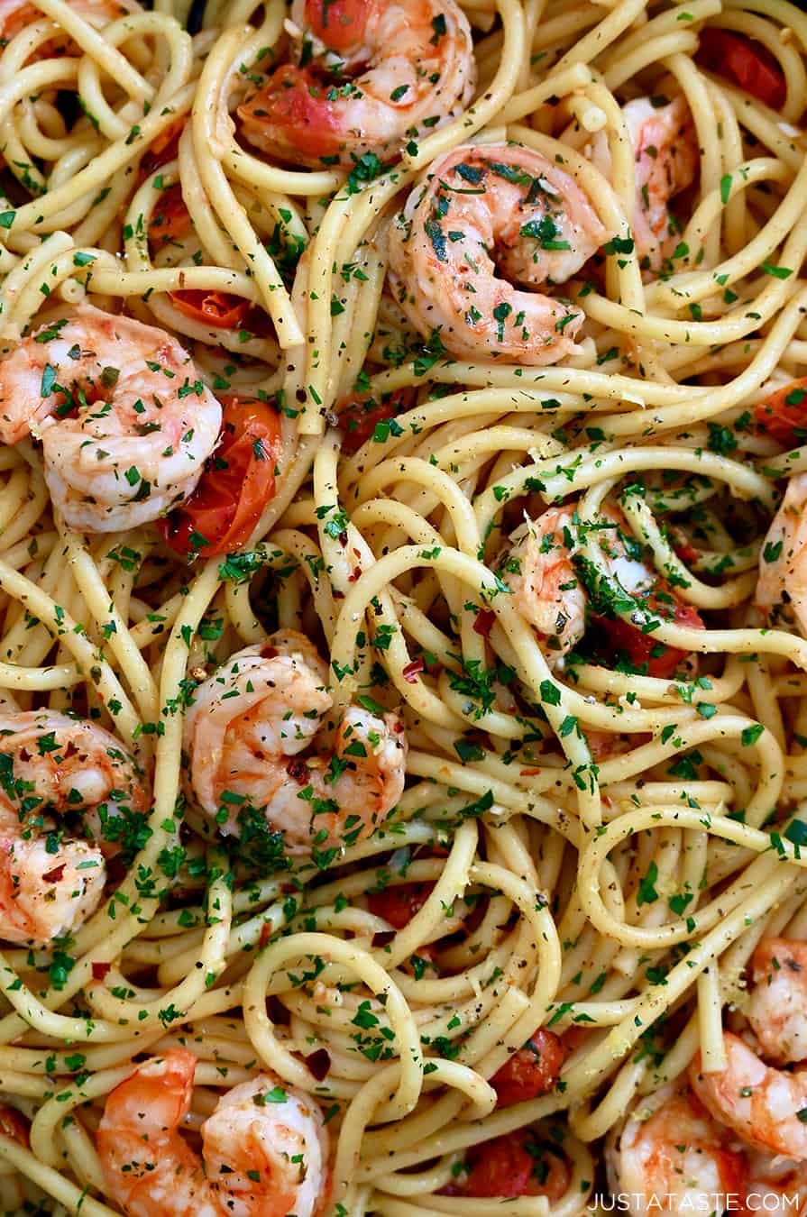 A close-up view of shrimp scampi with linguine and cherry tomatoes garnished with fresh herbs