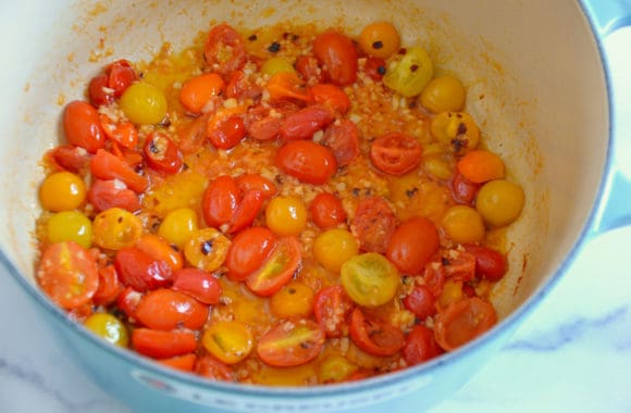 Large sauté pan with cherry tomatoes, garlic and chili flakes