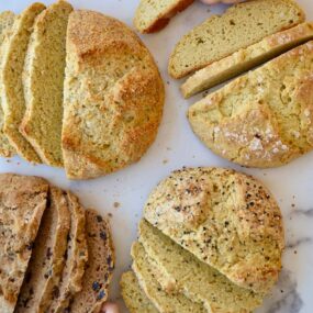 Four loaves of sliced bread with little kids hands grabbing slices