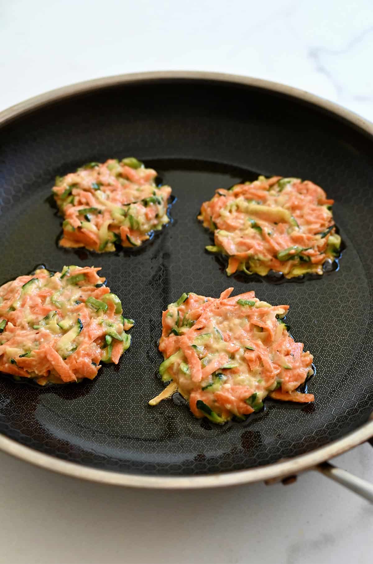 Pan-frying veggie fritters in a little bit of olive oil.