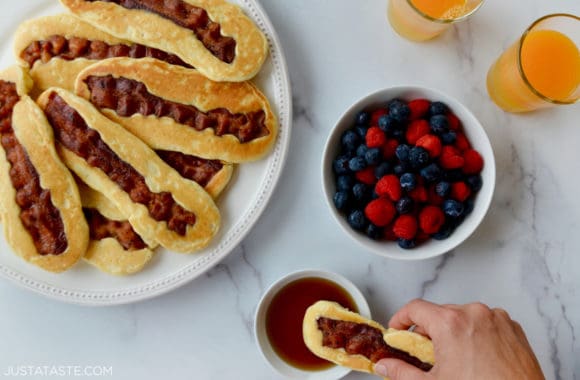 Stack of homemade bacon pancake dippers on plate next to small bowl with fresh berries 