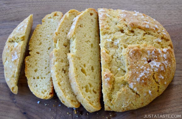 A loaf of homemade bread cut into slices on a wood cutting board