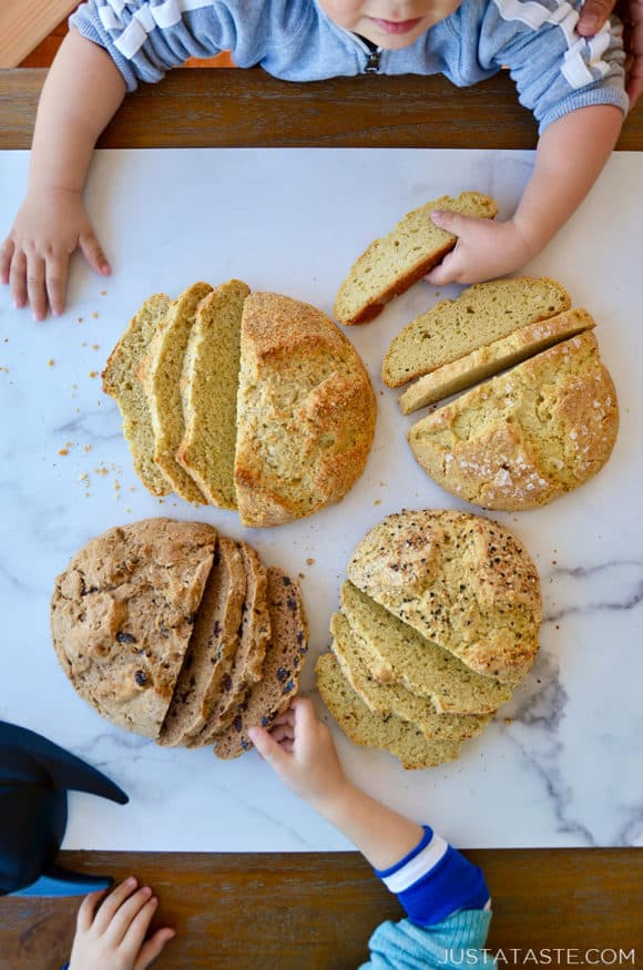 Little boys reaching for sliced loaves of bread on a table