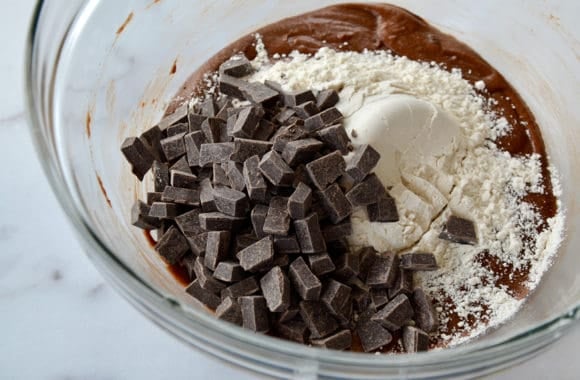 A glass bowl with brownie batter and chocolate chunks