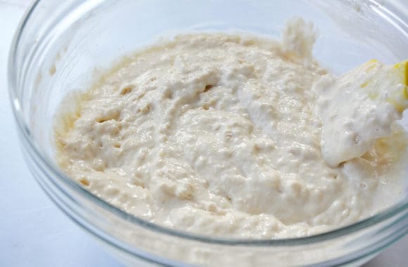 Glass bowl containing lumpy batter with spatula